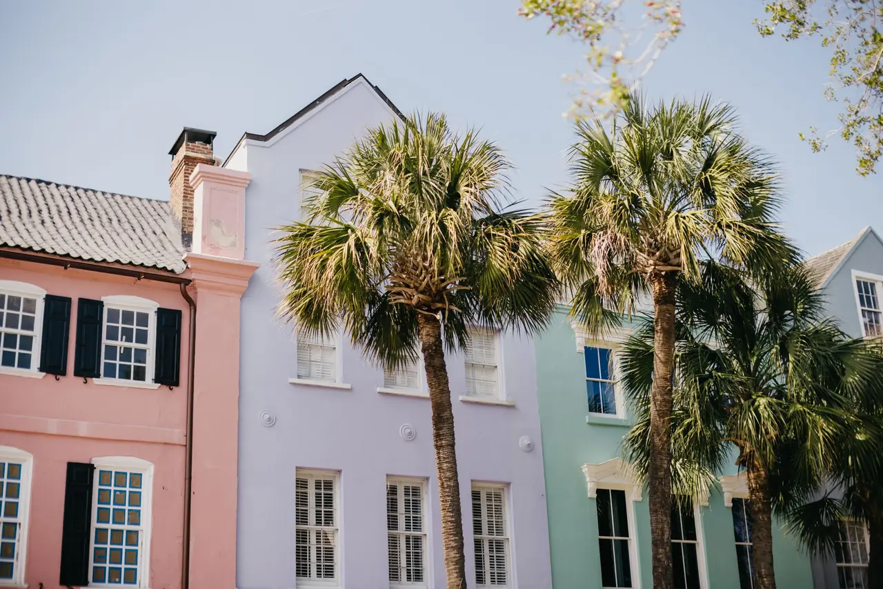 Pastel pink, lavender and mint facades of Rainbow Row on East Bay Street in Charleston, South Carolina, framed by palmetto trees