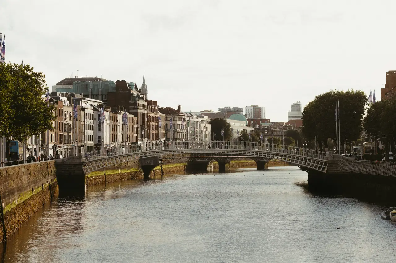The Ha'penny Bridge arching over the River Liffey in Dublin, with the quayside buildings of Bachelors Walk and the city centre behind