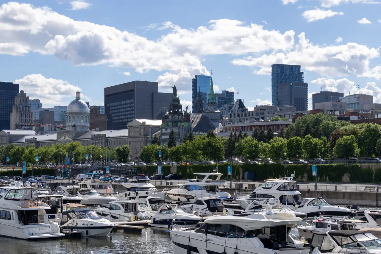 Yachts in the Old Port of Montreal below the silver dome of Bonsecours Market and the Old Montreal skyline