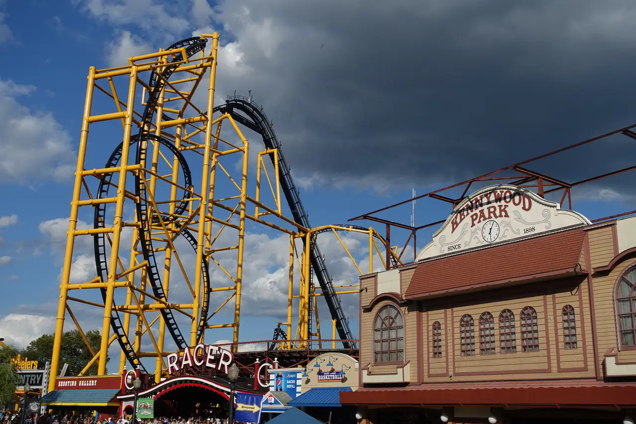 The yellow-and-black Steel Curtain roller coaster rising over the Kennywood Park entrance building and the Racer