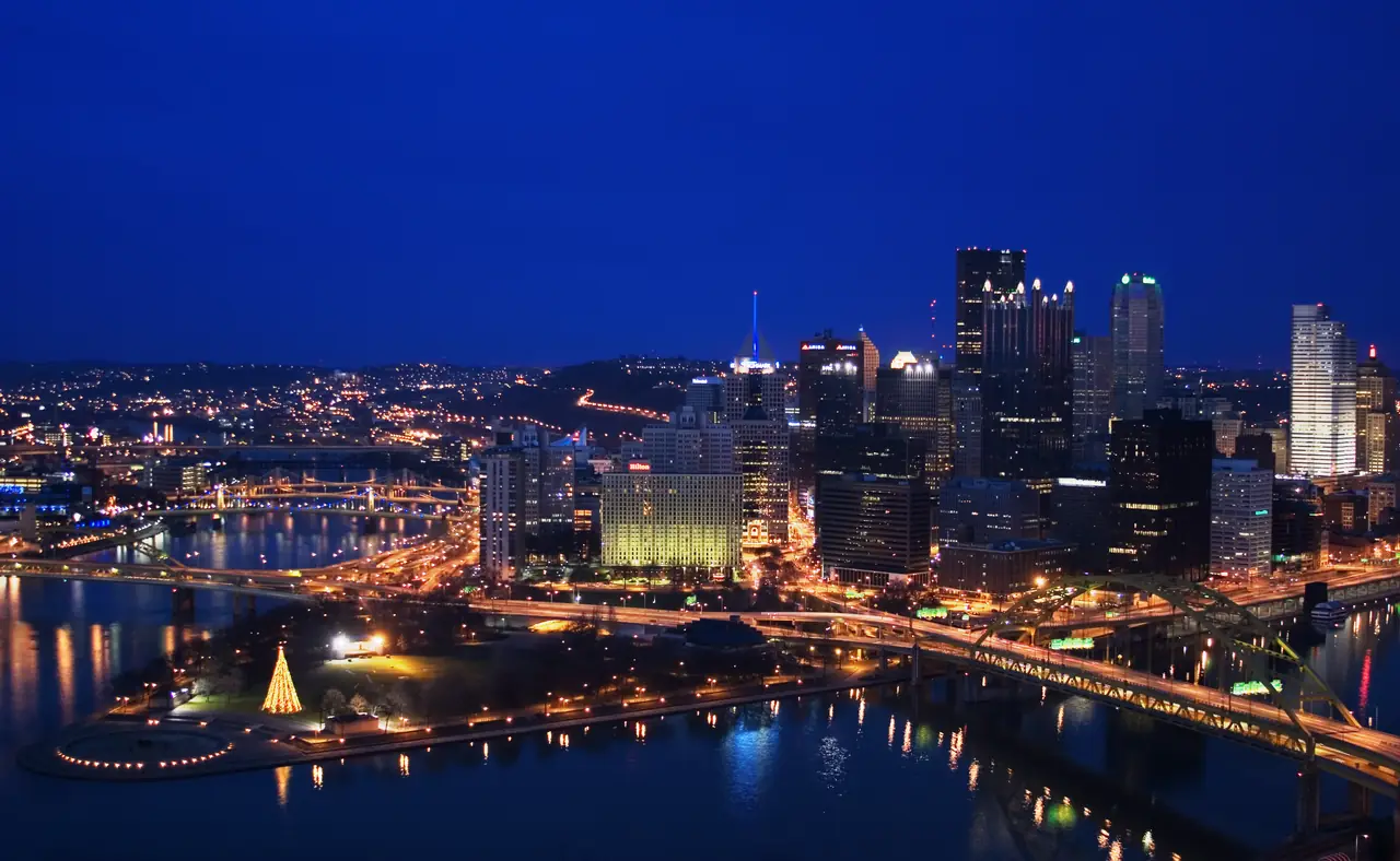 Downtown Pittsburgh lit up at blue hour from Mount Washington, with Point State Park, the rivers and the Fort Pitt Bridge below